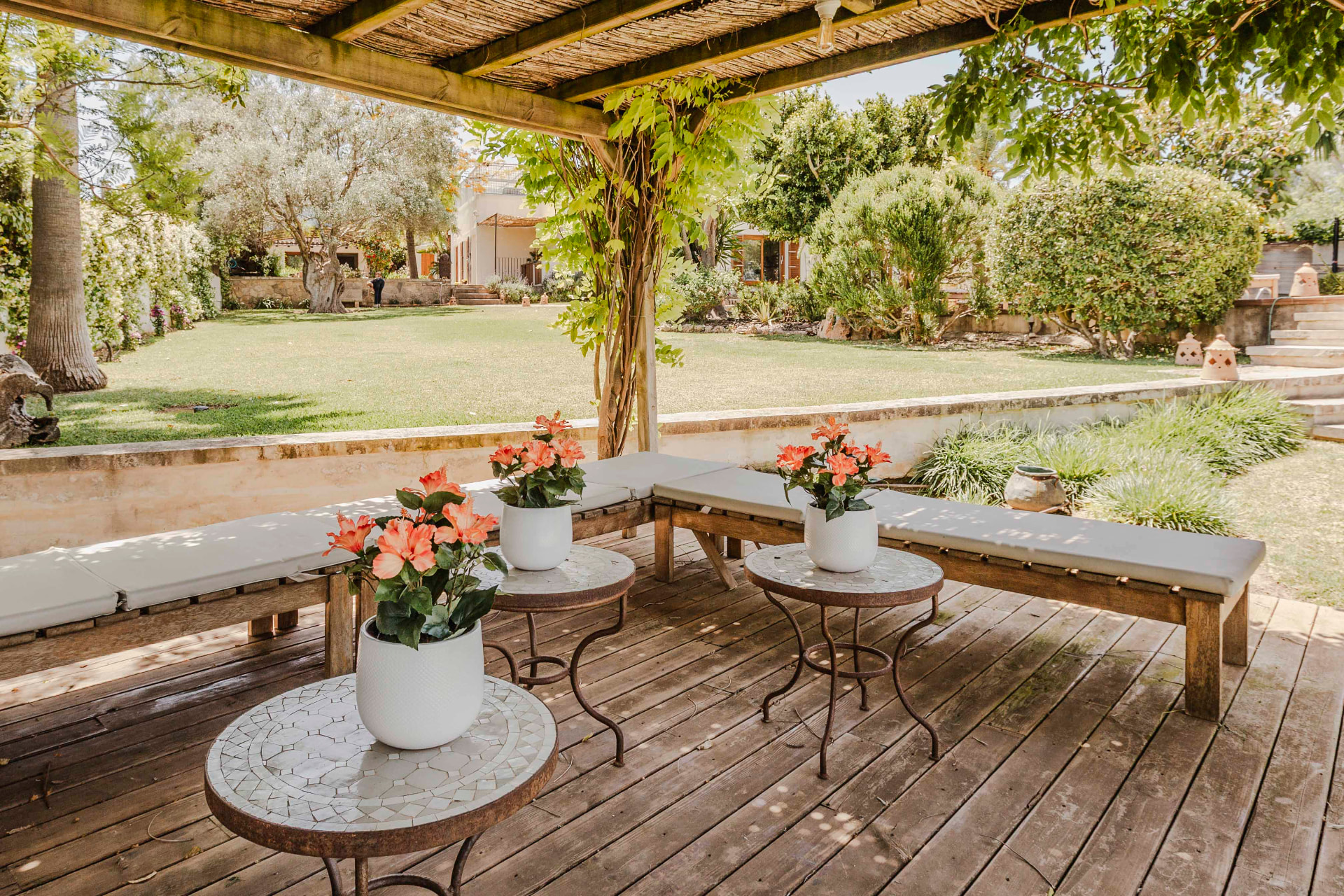 A shaded pergola terrace with cushioned benches looking over the garden