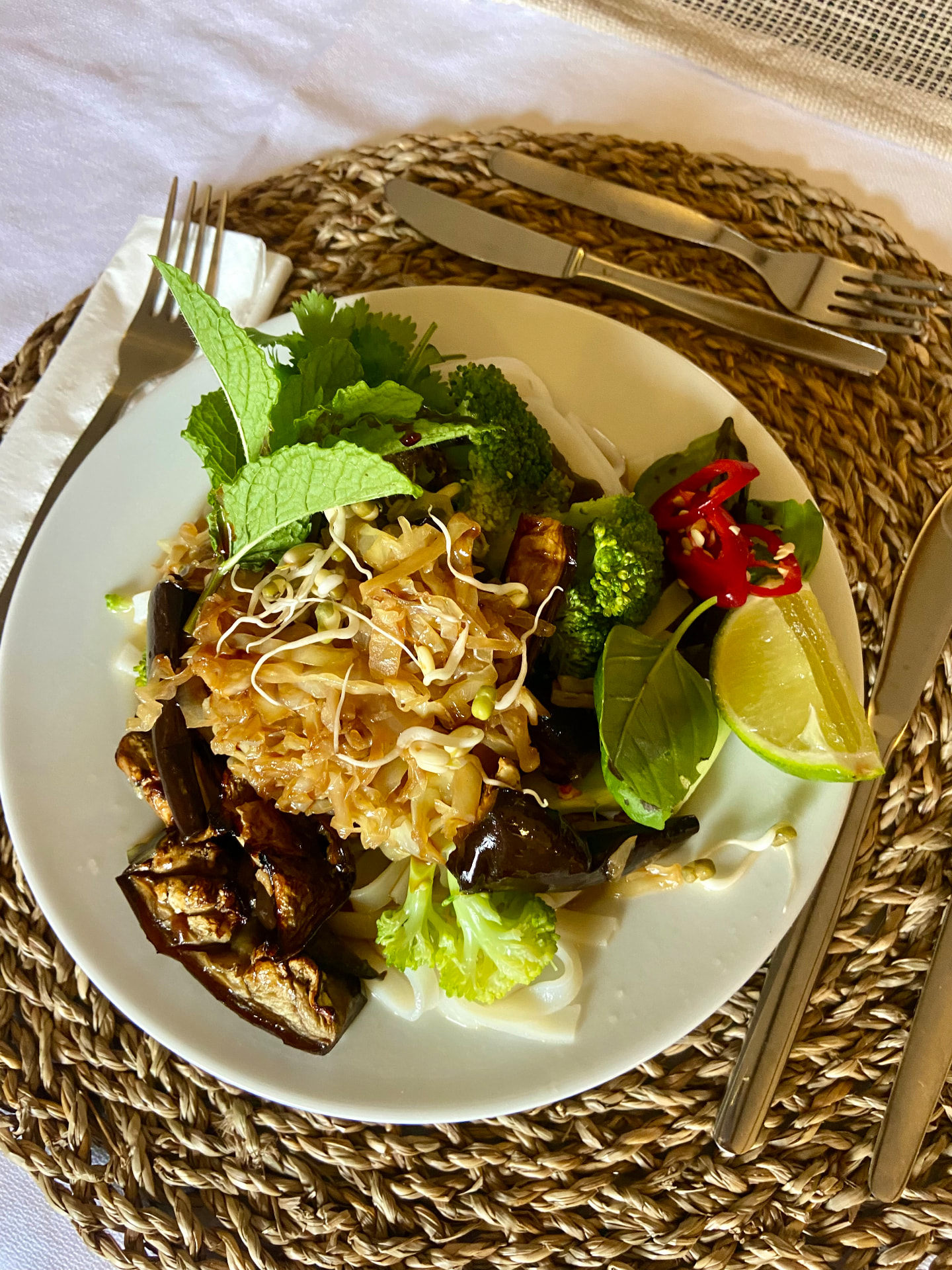 A plated vegetable and noodle dish with herbs and lime