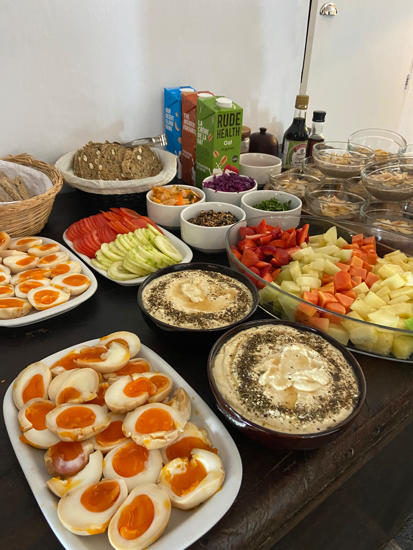 A brunch table with eggs, hummus, fruit and fresh bread