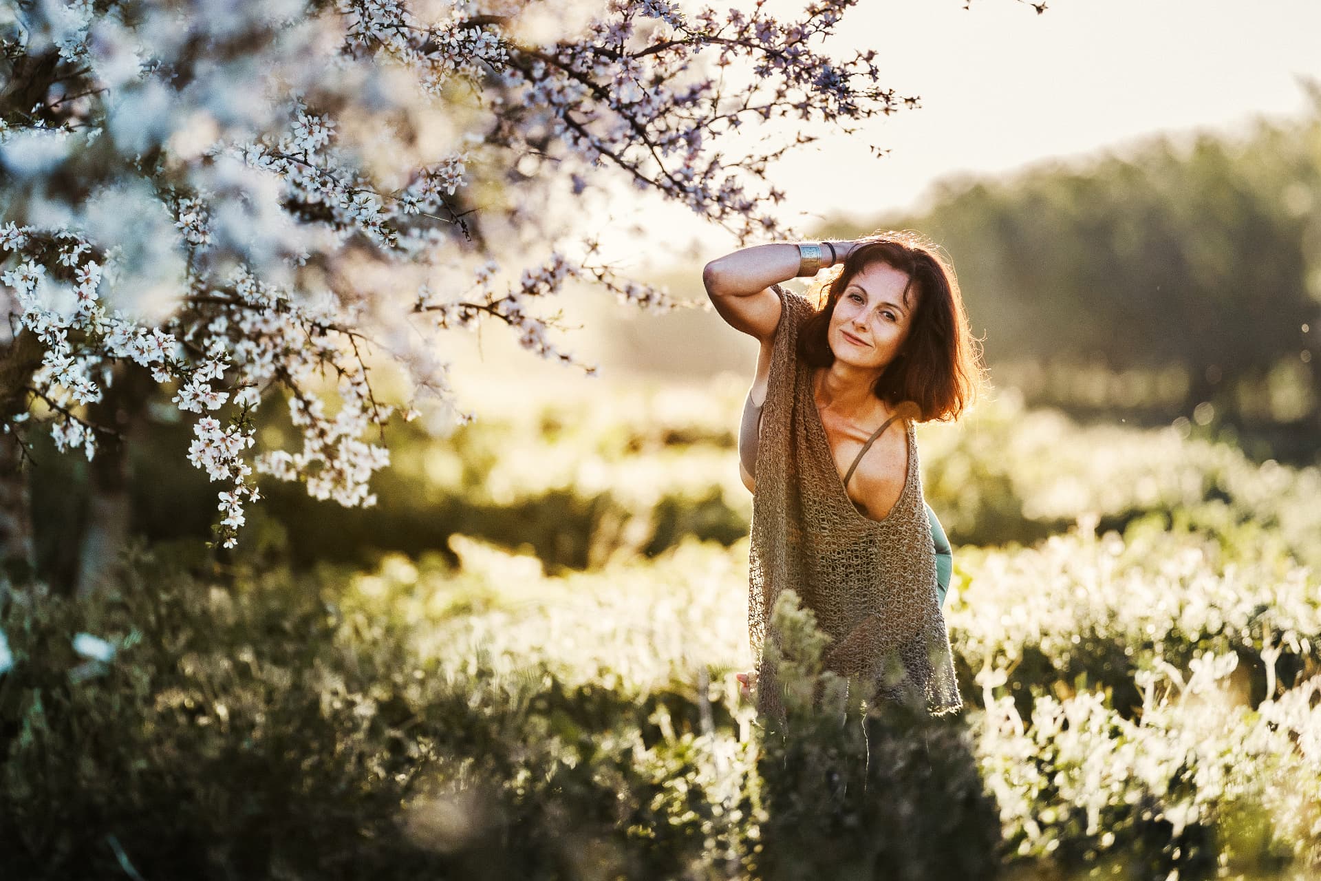 Saskia Griffiths standing among almond blossom in evening light