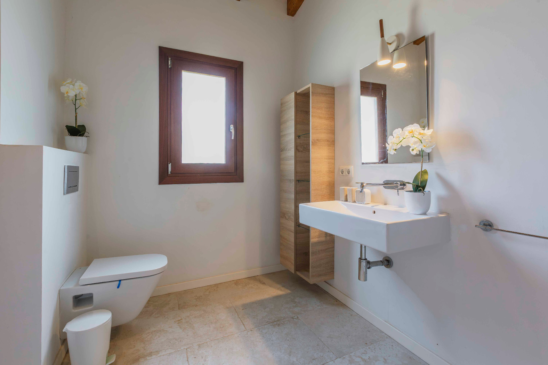 A calm, light-filled bathroom with natural stone floors